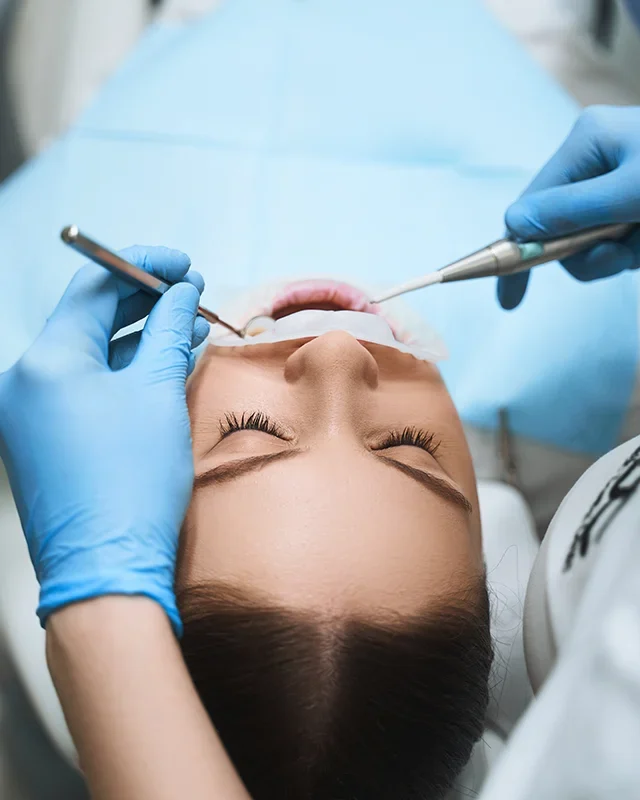 A woman in a dentist chair with her mouth open, undergoing dental treatment during a dental crisis
