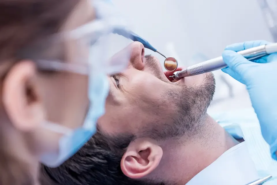 dentist-in-protective-mask-and-glasses-curing-teeth Average Charges for Root Canal Treatment