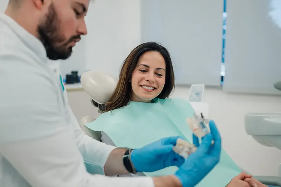 dentist-showing-dentures-to-patient-in-dental-clinic Which Type of Dentist Performs Dental Implants: Choosing a Provider Without Guesswork