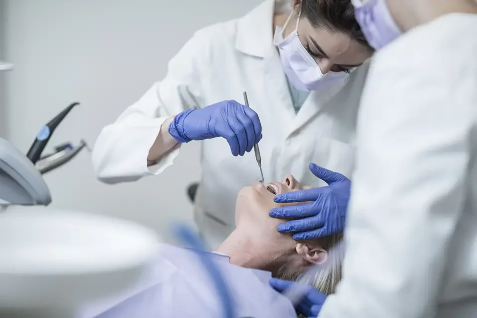 female-dentist-examining-patient-with-mouth-mirror How Dental Insurance Helps in Making Dental Crowns Budget-Friendly