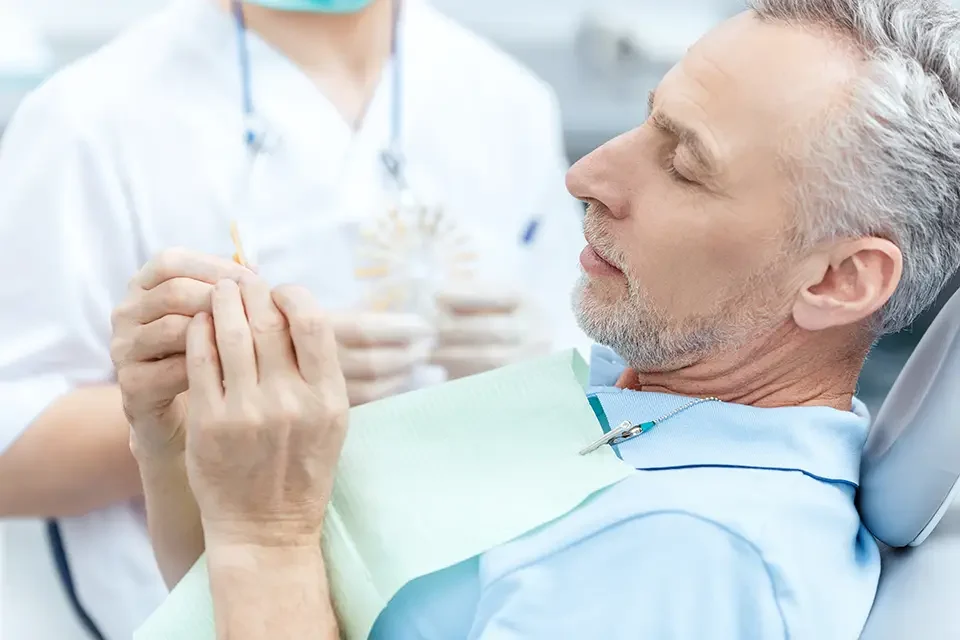 mature-patient-looking-at-tooth-sample Do Dental Implants Hurt? During the Procedure