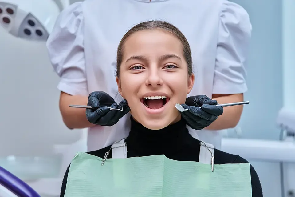 teenage-girl-in-dental-chair-with-hands-of-dentist What is Professional Teeth Cleaning?