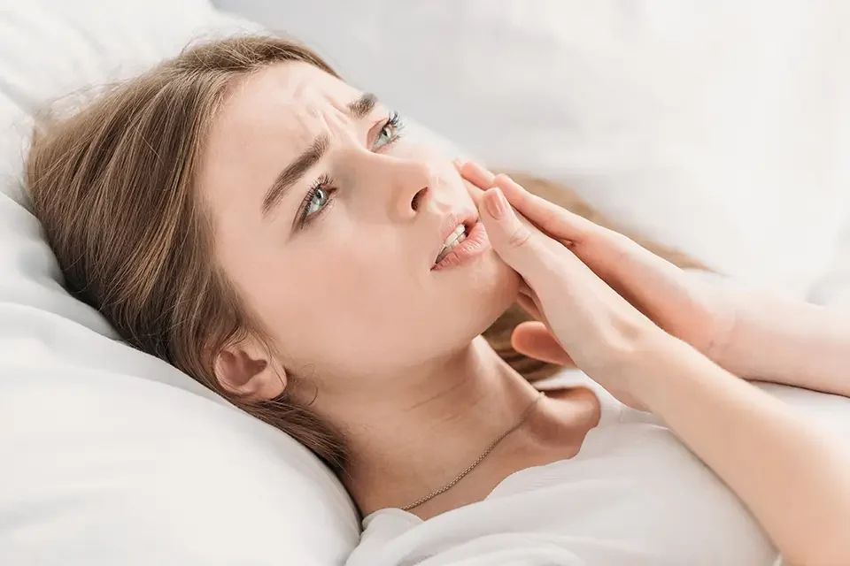 upset-girl-touching-cheek-while-suffering-from-toothache Signs You May Grind Teeth in Sleep